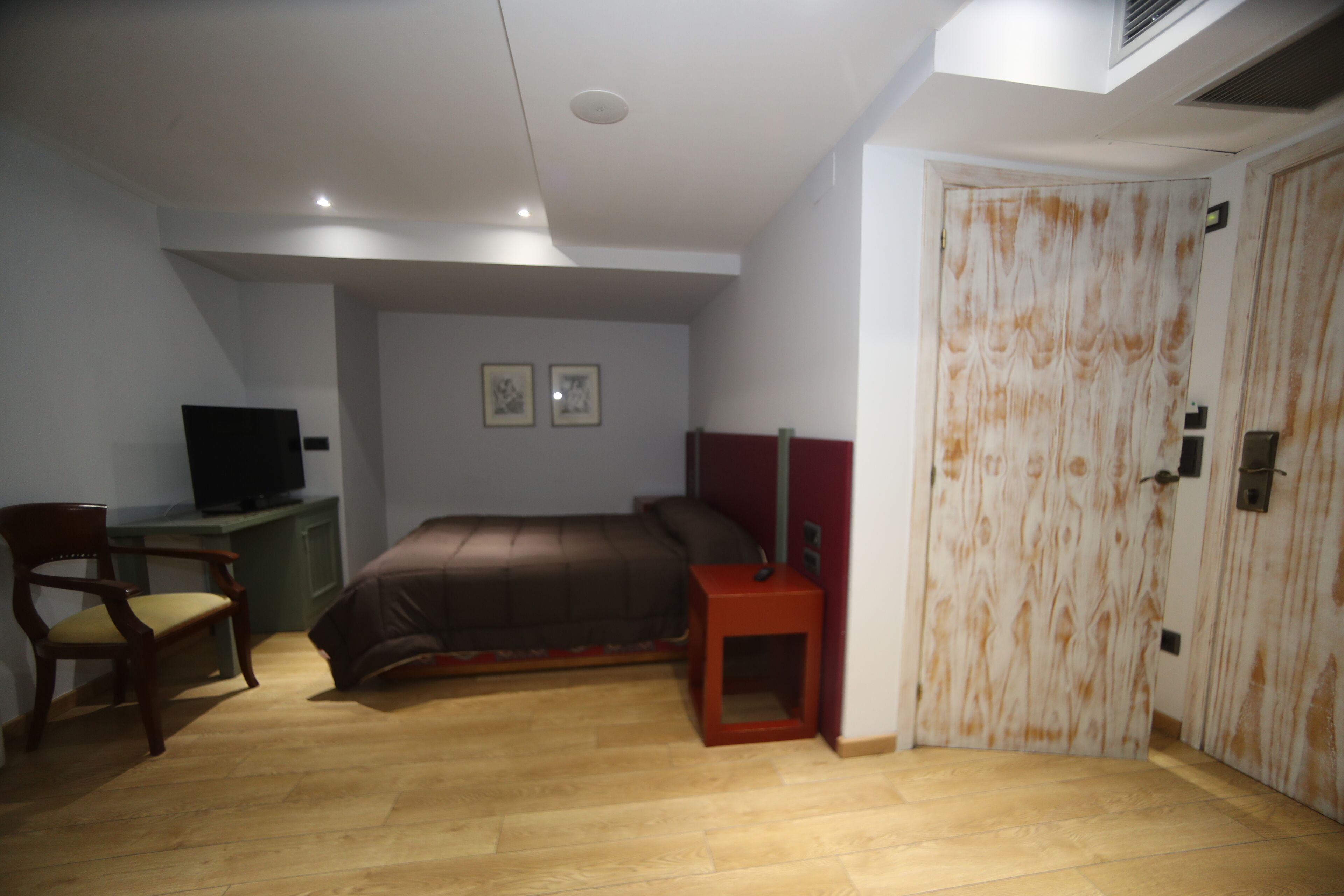 Un dormitorio con cama, escritorio con silla, televisor y armario.
