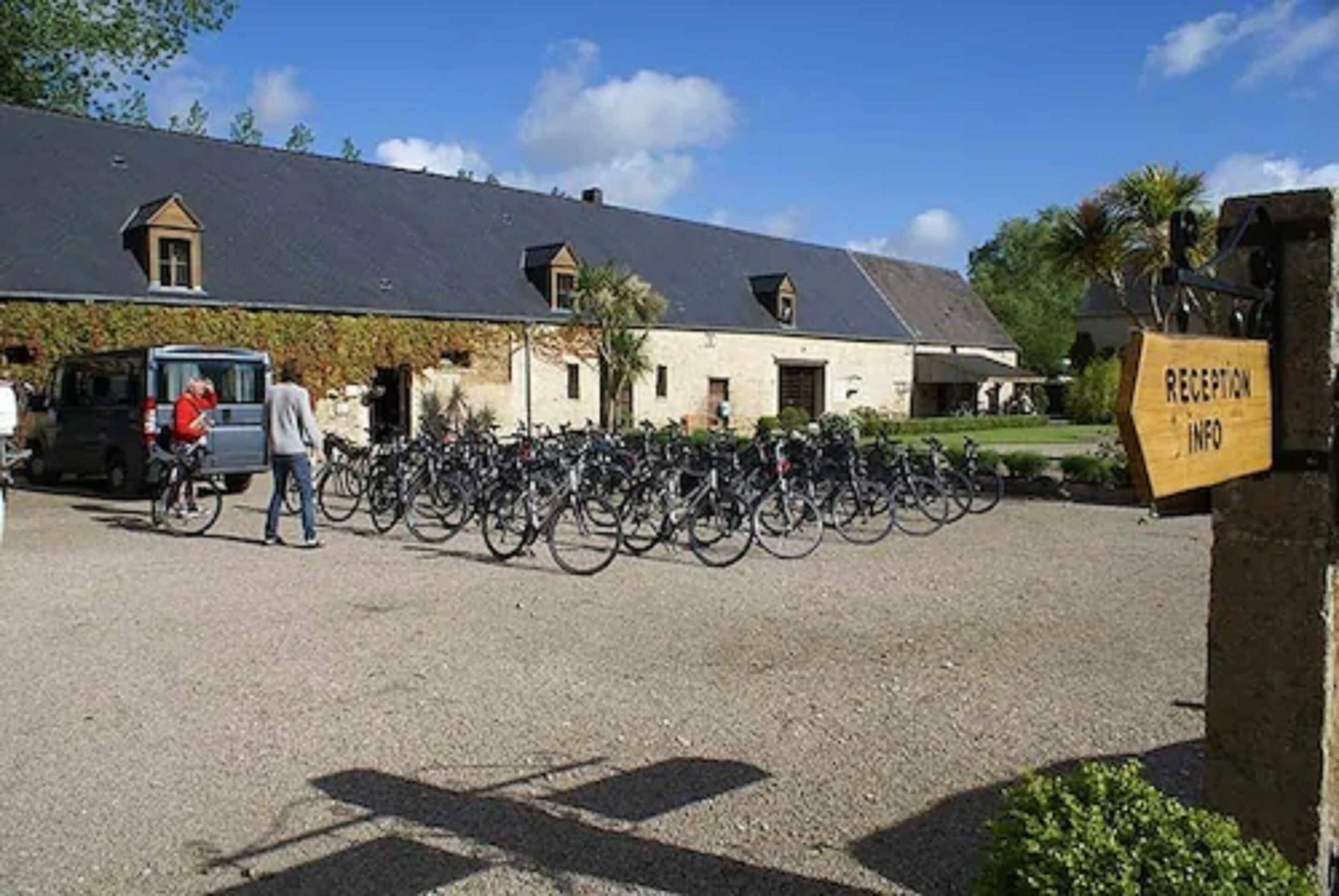 A building with a gravel driveway, bicycles parked in front, and a reception sign.