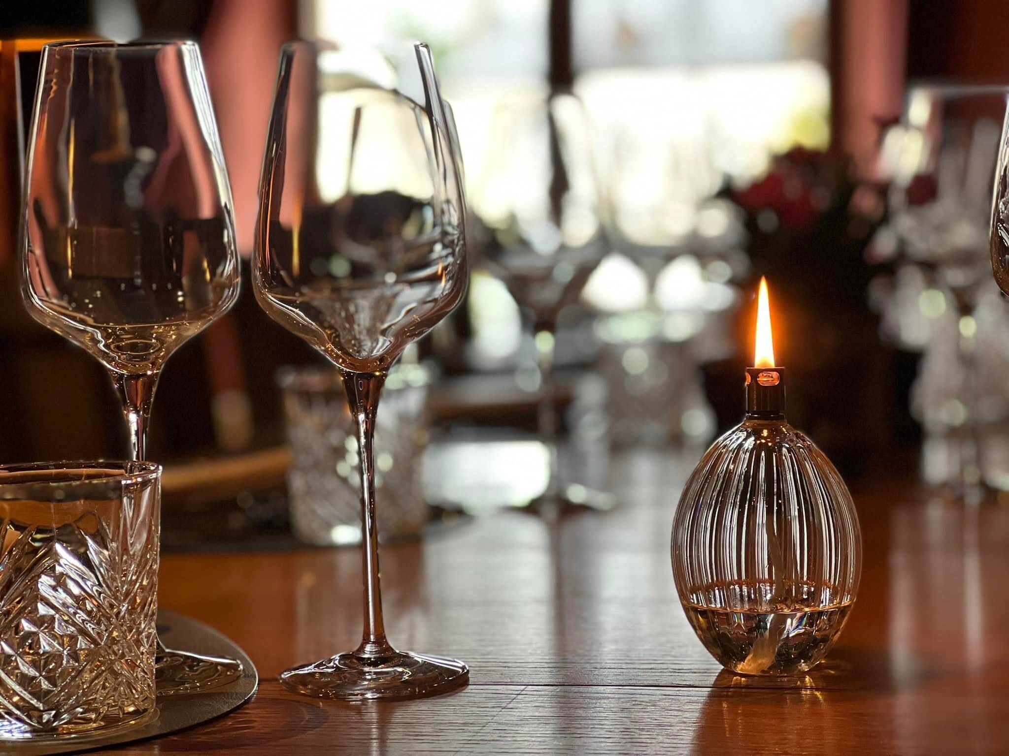 Un bar con varios vasos de vino y una vela encendida sobre una mesa de madera.