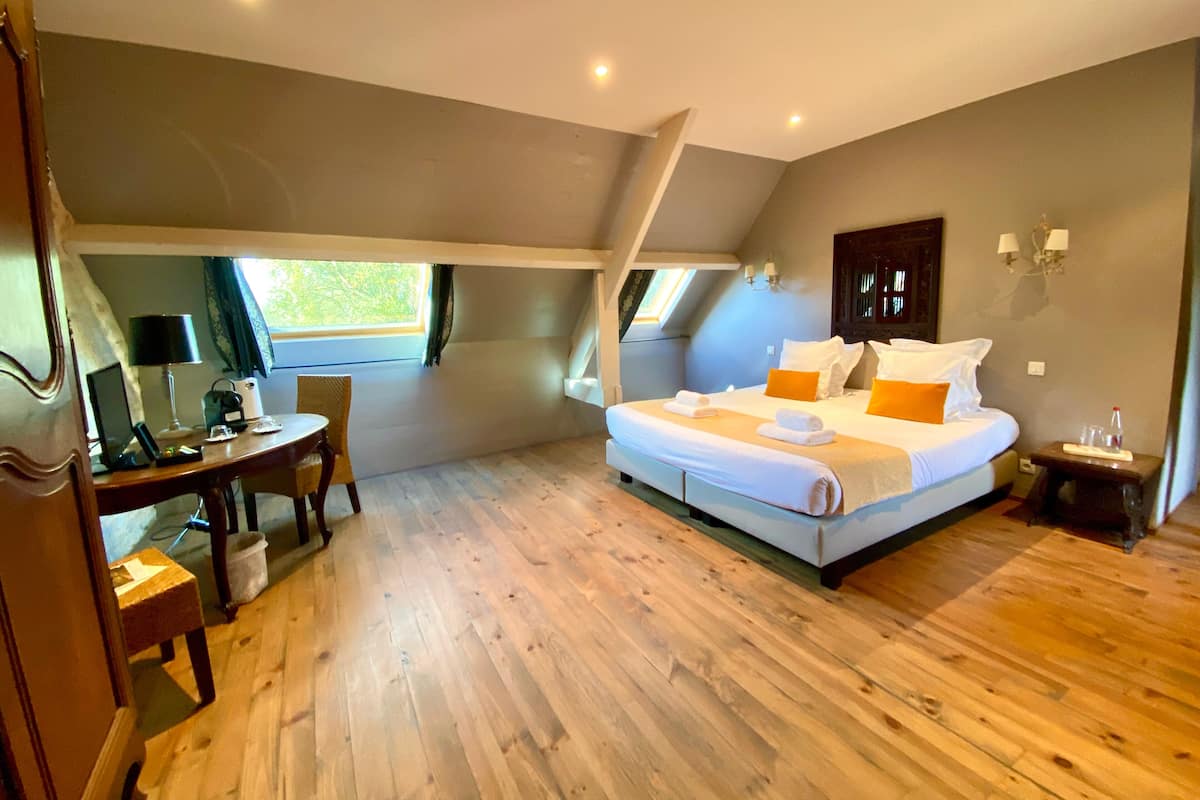 Une chambre avec un grand lit, un bureau avec une lampe et une chaise.