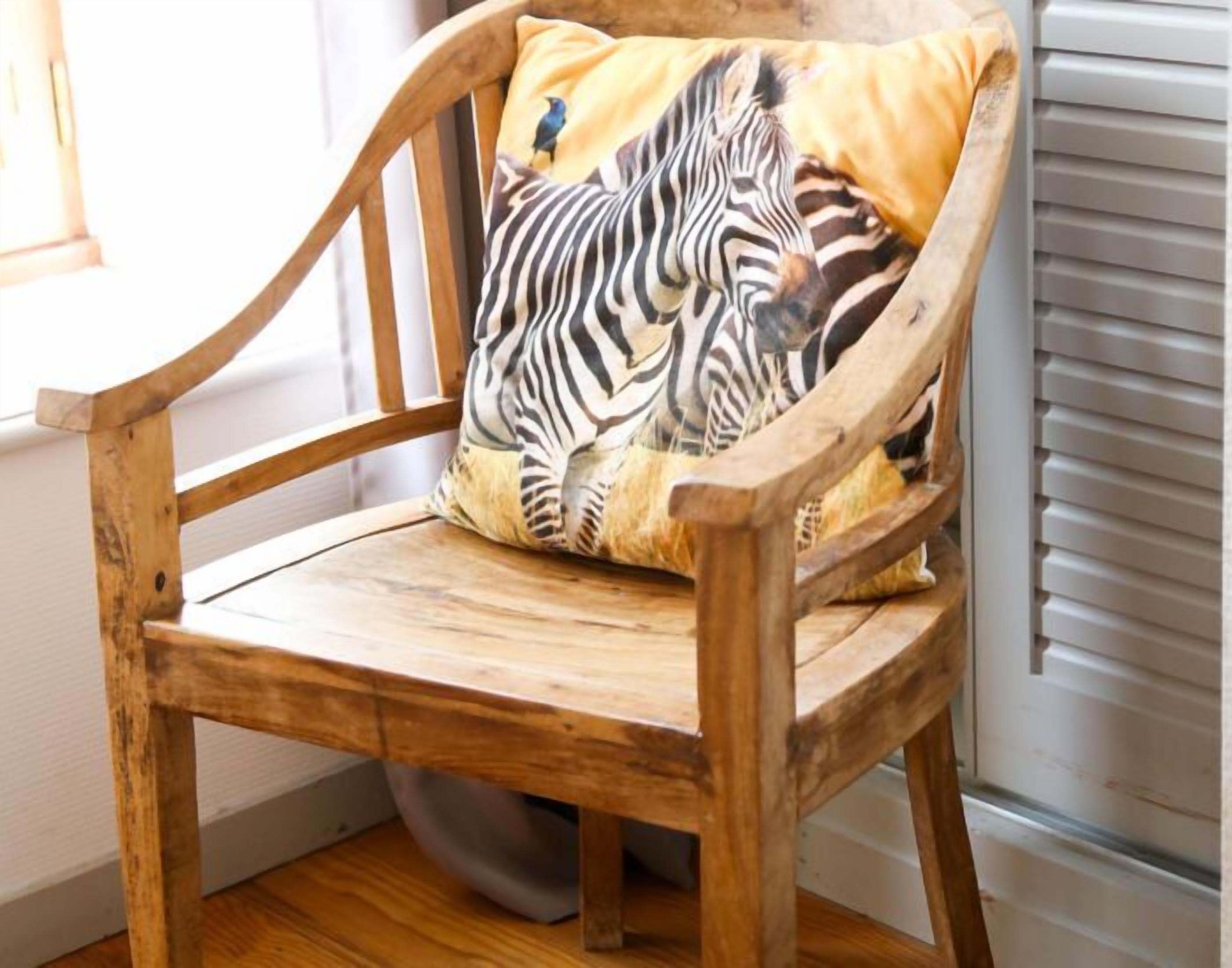 A wooden chair with a zebra-patterned pillow.