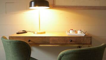 A desk with a lamp, two chairs, and a framed collage on the wall.