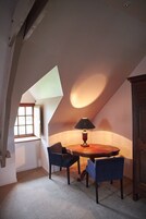 Un cuarto ático acogedor con una mesa de madera y dos sillas, una lámpara y una ventana.