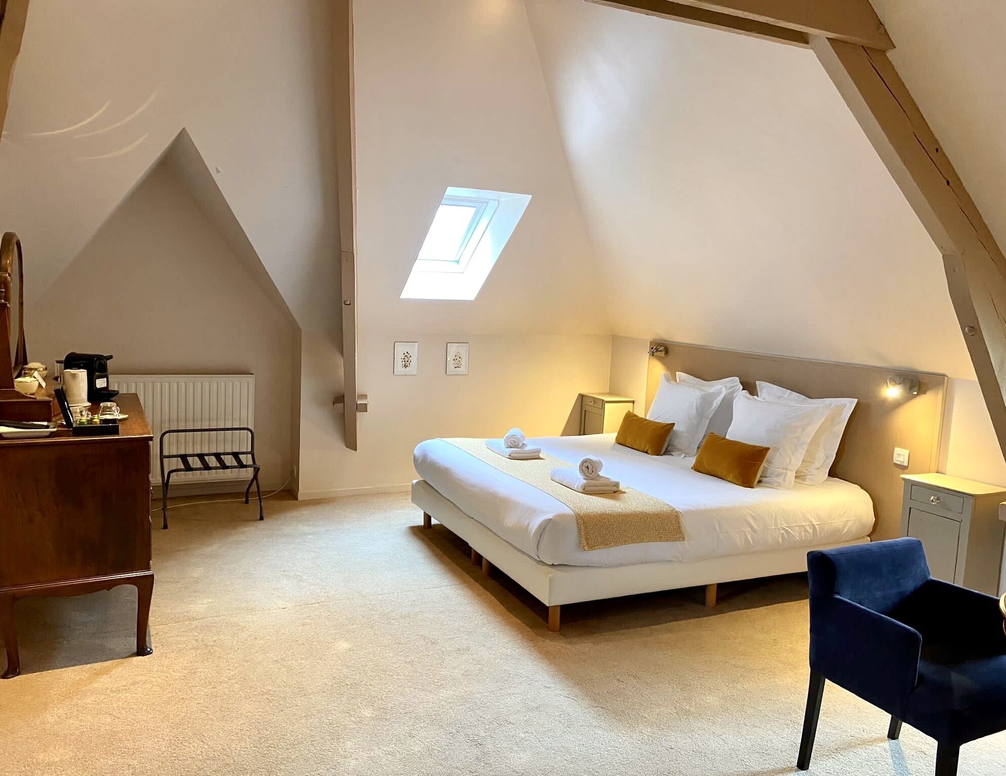 A bedroom with a bed, a desk, a chair, and a skylight.