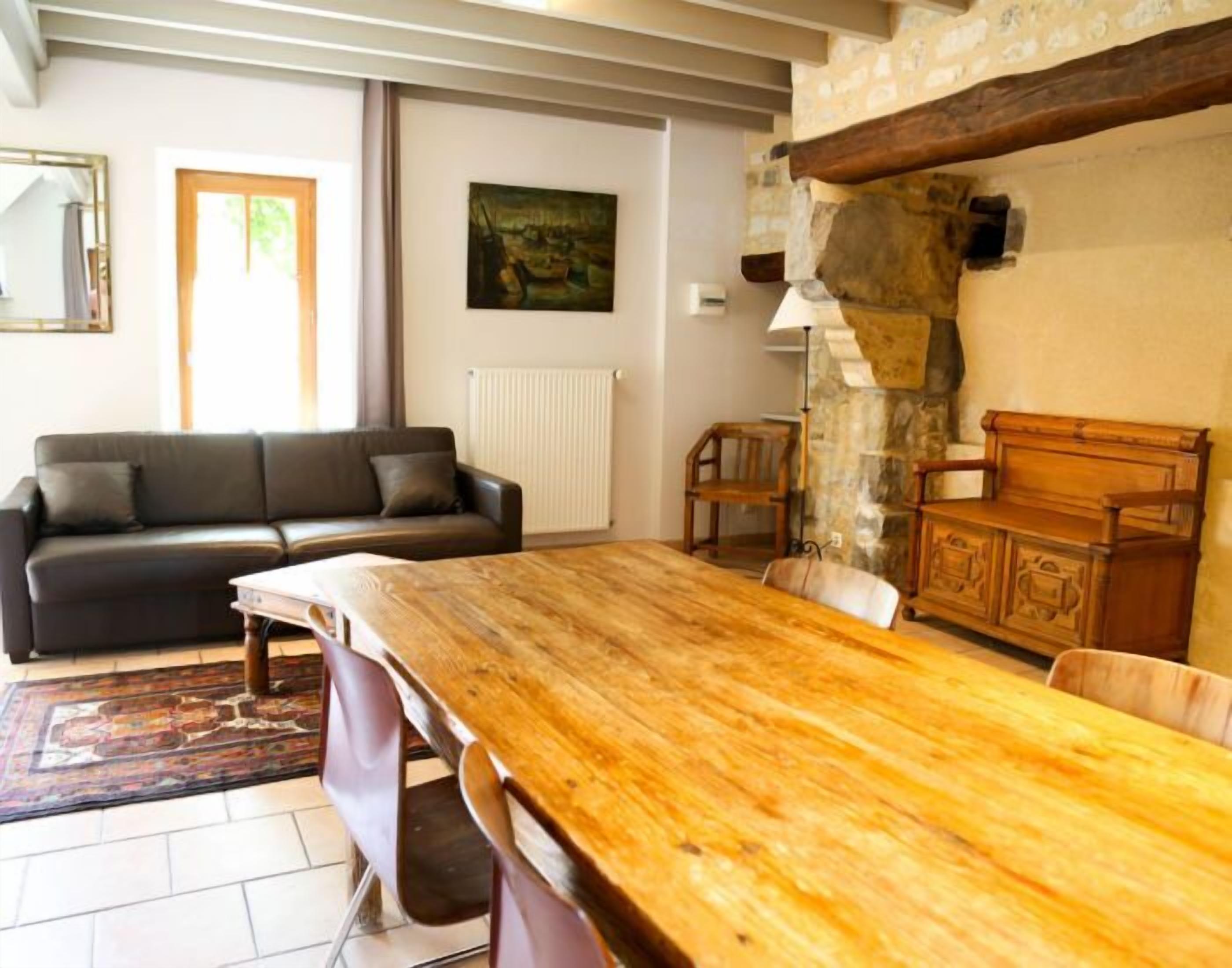 Een woonkamer met een houten eettafel, een bank en een stenen muur.