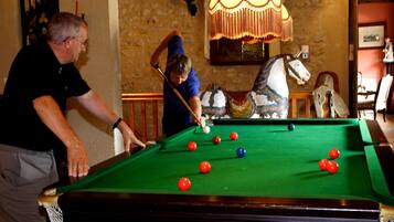 A pool table with balls in a room with stone walls and a chandelier.
