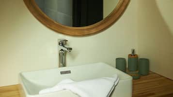 Un baño con un espejo redondo, un lavabo blanco y un mueble de tocador de madera.