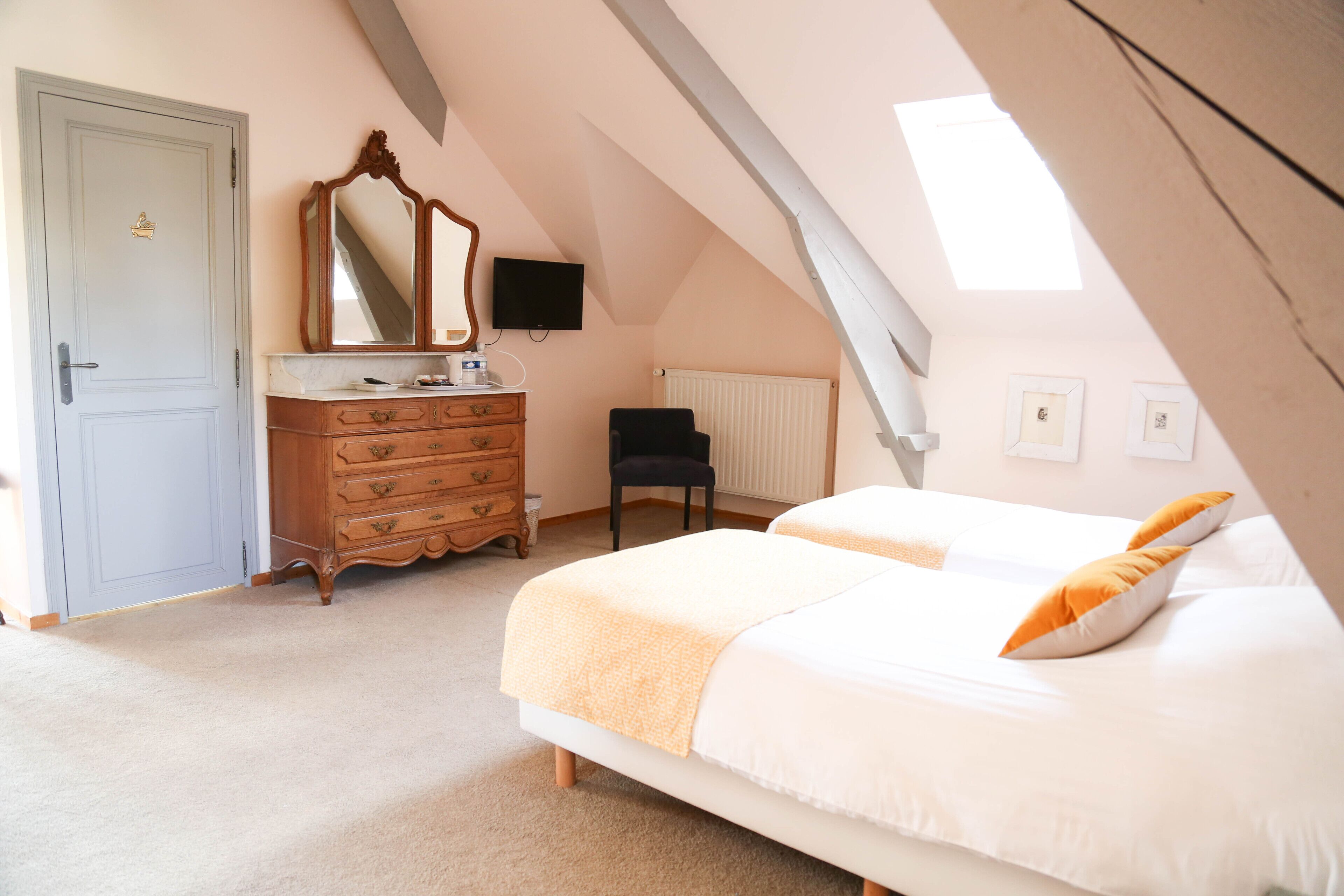 A bedroom with two beds, a dresser, a chair, a television, and a window with natural light.