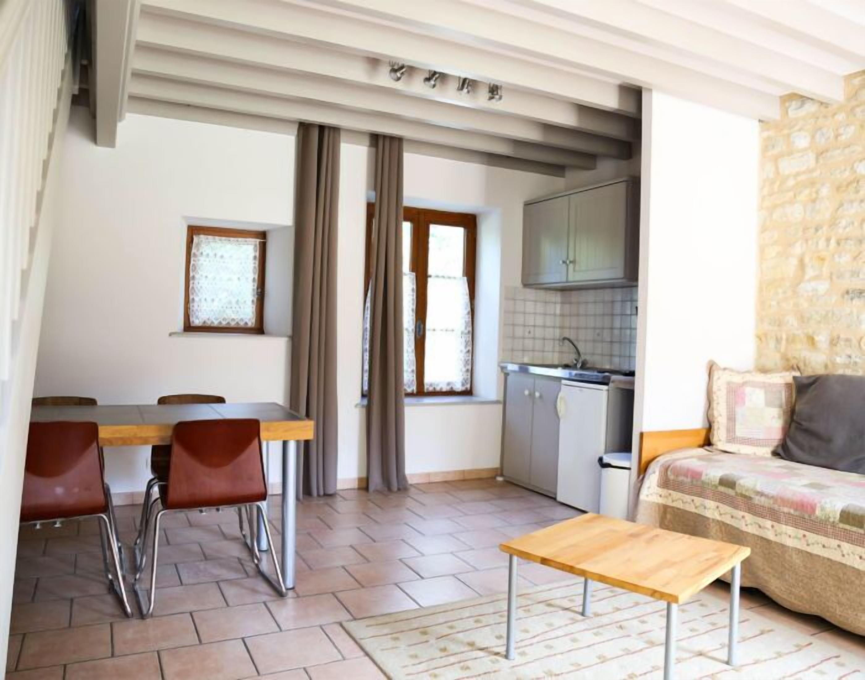 Un espacio habitable compacto con comedor, kitchenette y zona de estar.