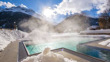 Een binnenzwembad, een buitenzwembad, ligstoelen bij het zwembad