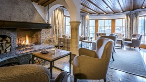 Una habitación acogedora con chimenea de piedra, asientos cómodos y ventanas amplias.