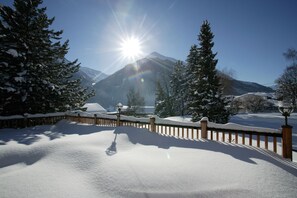 Ett snötäckt landskap med ett trästaket, en gatlykta och ett berg i bakgrunden.