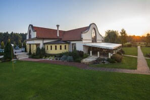 A two-story house with a red-tiled roof, a covered patio, and a well-maintained lawn. - Wellness hotel SPARK (Plavecký Štvrtok)