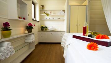 A hotel room with a bed, a vanity with a mirror, a sink, and shelves with towels and toiletries.