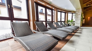 A row of wicker lounge chairs with a view of the outside through large windows. - Wellness hotel SPARK (Plavecký Štvrtok)