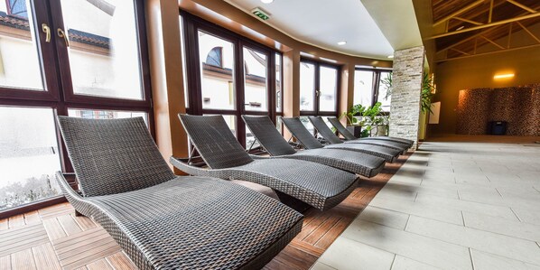 A row of wicker lounge chairs with a view of the outside through large windows.