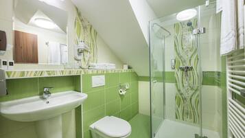 Une salle de bain équipée d’un lavabo, de toilettes et d’une douche à parois de verre.