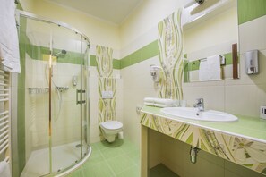 A bathroom with a glass-enclosed shower, a toilet, and a sink with a mirror above it. - Wellness hotel SPARK (Plaveck ý Štvrtok)
