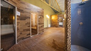 A spacious indoor area with a wooden floor, a glass door leading to a room, and a blue-tiled shower area. - Wellness hotel SPARK (Plavecký Štvrtok)