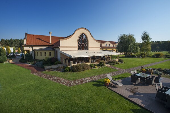 A hotel with a large patio area, outdoor seating, and a Coca-Cola branded awning. - Wellness hotel SPARK (Plavecký Štvrtok)