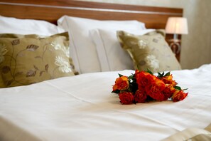 A neatly made bed with white linens and a bouquet of red roses. - Wellness hotel SPARK (Plavecký Štvrtok)