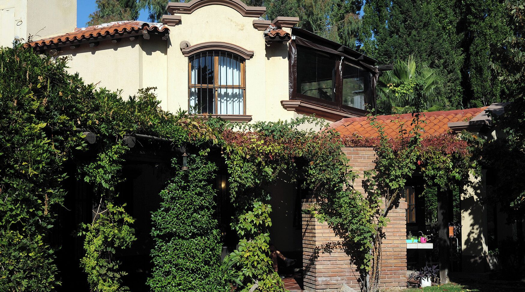 Um edifício com fachada em estuque, telhado ladrilhado e janela emoldurada em madeira.