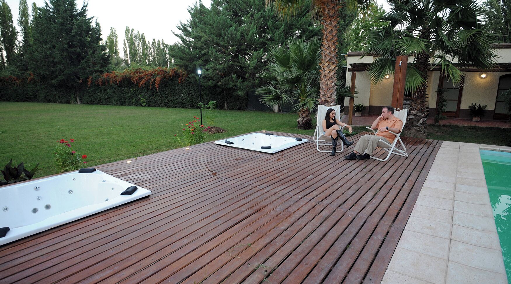 Une terrasse en bois avec deux bains à remous et deux chaises longues.