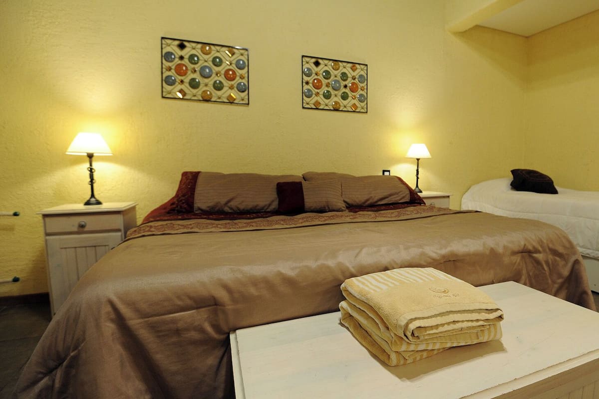 Une chambre d’hôtel avec un grand lit, deux lampes de chevet et des œuvres d’art décoratives au mur.