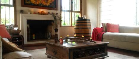 Una sala de estar acogedora con chimenea, una mesa de centro de madera y un ventanal grande.