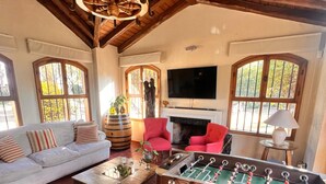A cozy living room with a foosball table, a sofa, and a television. - Pilgrim's Rest (Chacras de Coria)