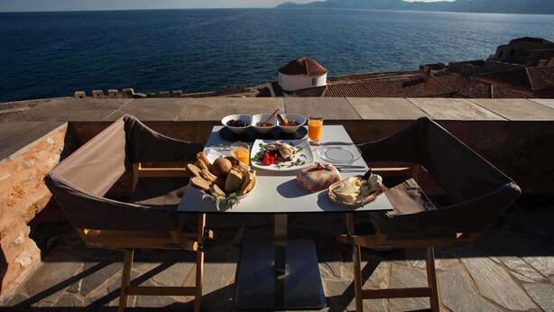 Una mesa dispuesta con alimentos para el desayuno y vistas al mar.