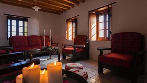 Una habitación acogedora con vigas de madera, sillas rojas con estampado y velas encendidas.