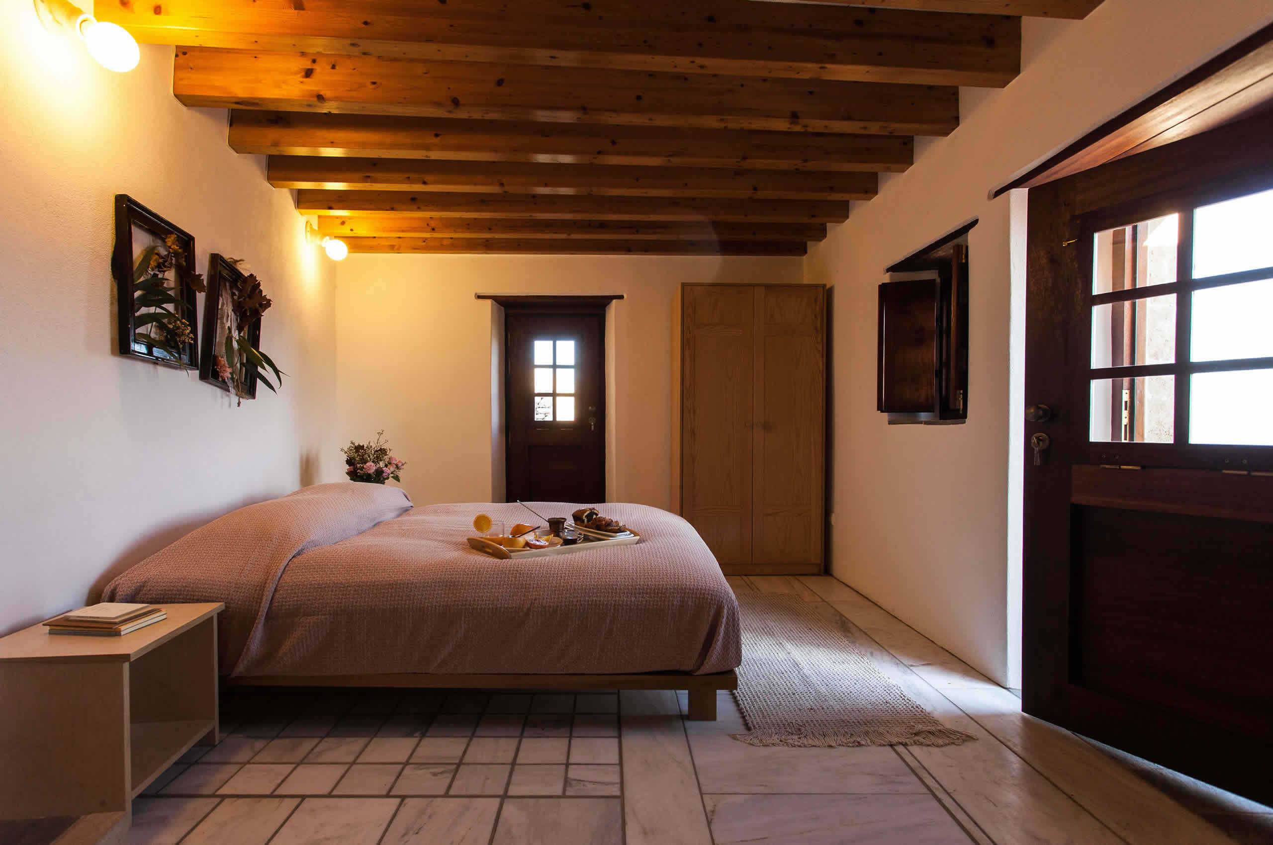 Un dormitorio con cama, mesita de noche, puerta de madera y ventana.