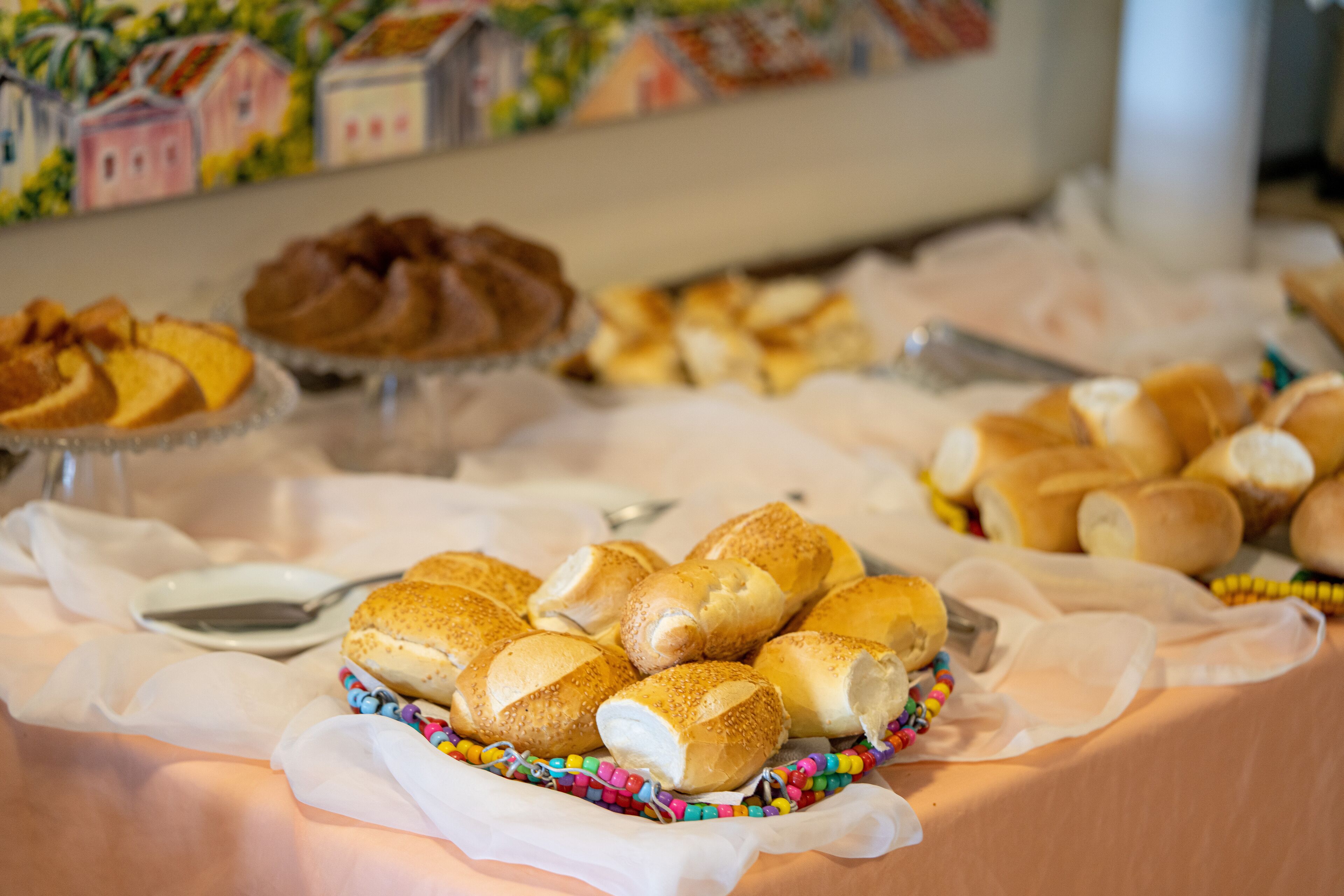 A buffet table with various baked goods, including rolls and pastries, arranged on a tablecloth.