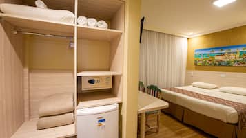 Una habitación de hotel con literas, una mesita pequeña, un refrigerador y un cuadro en la pared.