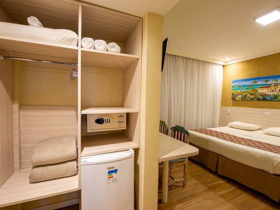 Une chambre d’hôtel avec un lit superposé, une petite table, un réfrigérateur et un tableau au mur.