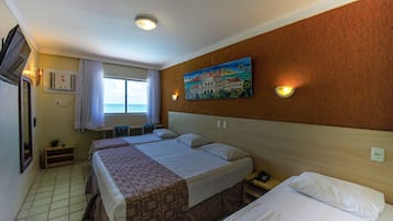 A hotel room with two beds, a painting on the wall, a window with curtains, and a view of the sea.