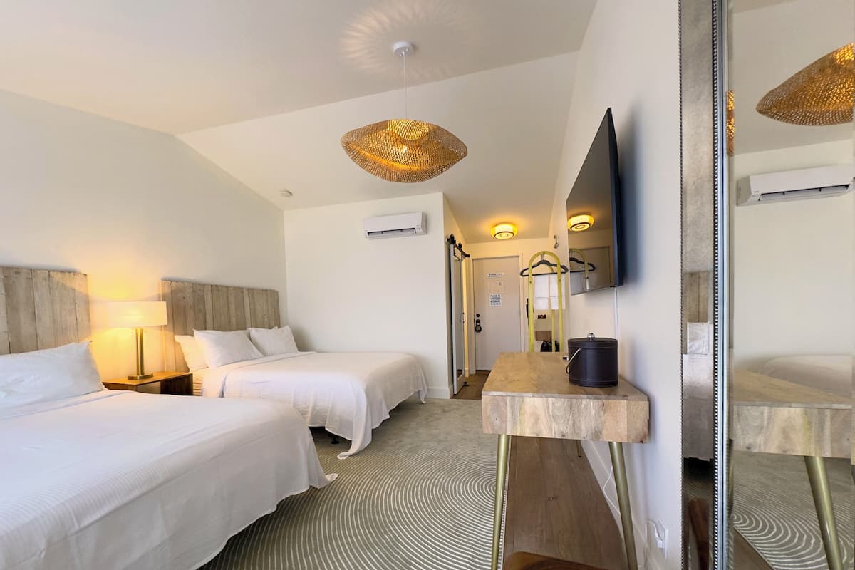 Een hotelkamer met twee bedden, een spiegel, een flatscreen-televisie en een kleine tafel.