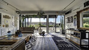 A spacious living room with a large window, a sofa, a coffee table, and a rug with text.