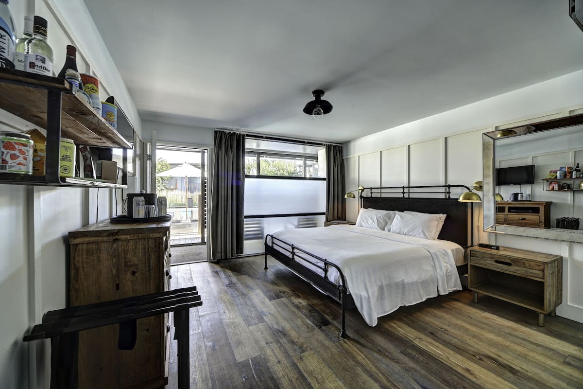 Een slaapkamer met een bed, houten meubels, een plank met spullen, een raam en een plafondventilator.