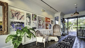 A spacious hallway with a large mirror, a potted plant, a white armchair, and a rug with words.