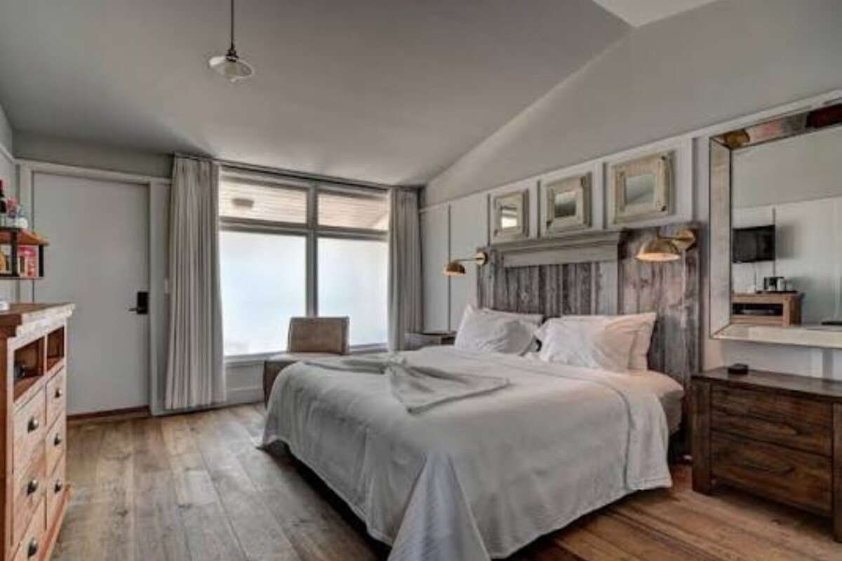 Ein Schlafzimmer mit einem großen Bett, einem Nachttisch, einem Sessel, einem Kleiderschrank und einem Fernseher.