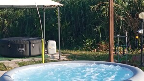 Un jacuzzi gonflable de la marque Lay-Z-Spa, entouré de verdure et doté d’un espace abrité.