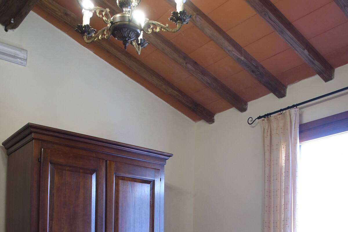 Een slaapkamer met twee bedden, een houten garderobe, een stoel en een raam met gordijnen.