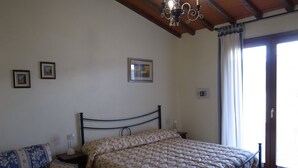 Une chambre à coucher avec un lit, une table de chevet, une chaise et une fenêtre avec des rideaux.