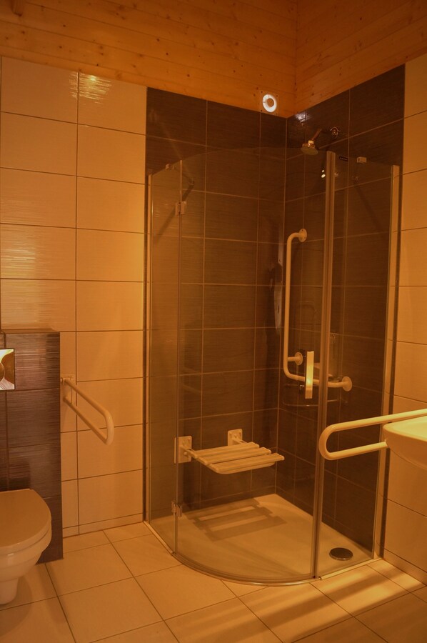 A bathroom with a glass-enclosed shower, a toilet, and a sink. - Domki Onyx (Mielno)