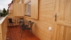 Una terraza de madera con dos sillas y una mesa, una ventana y una puerta.