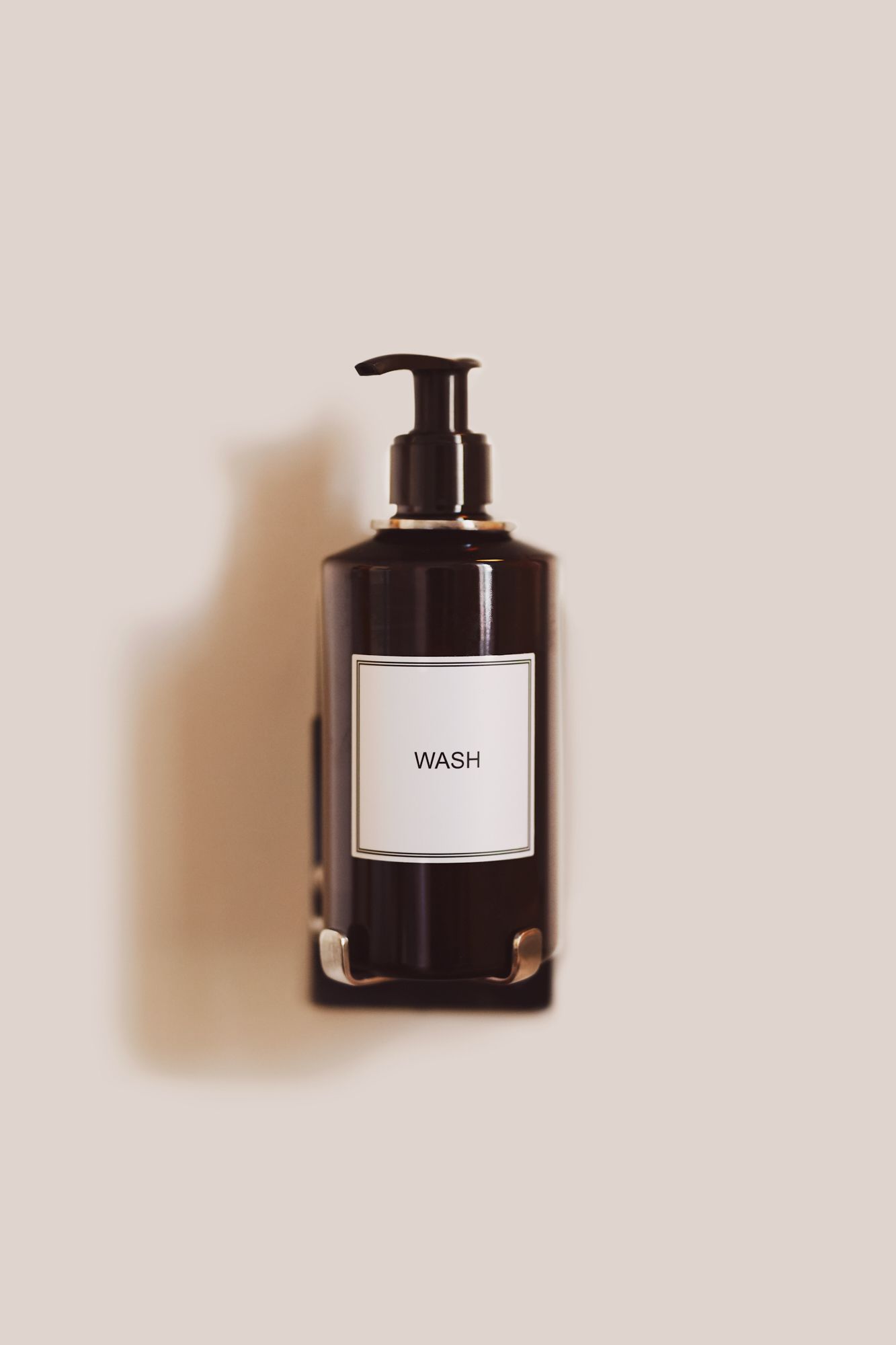 En sort flaske med pumpe og etiket med teksten 'WASH'.