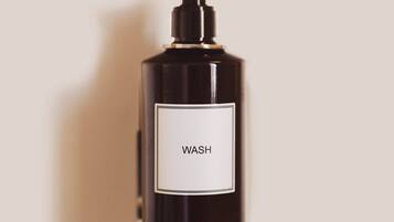 En sort flaske med pumpe og etiket med teksten 'WASH'.