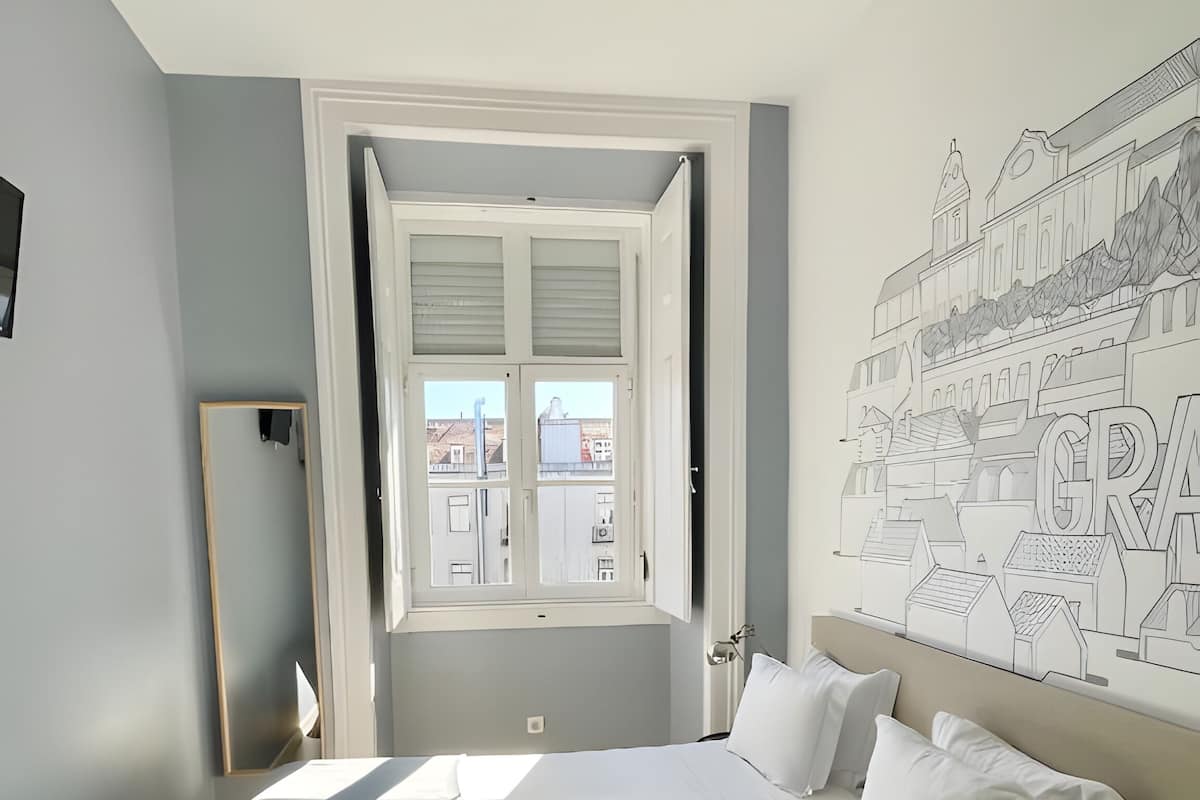 A bedroom with a bed, a window, and a wall mural.